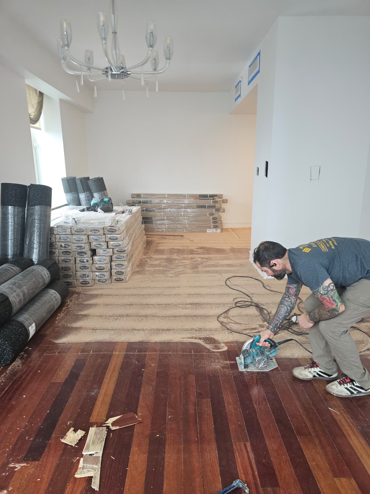 Demolition of the old damaged Brazilian cherry floor with rolls of soundproofing and new oak boxes staged in a SoHo apartment