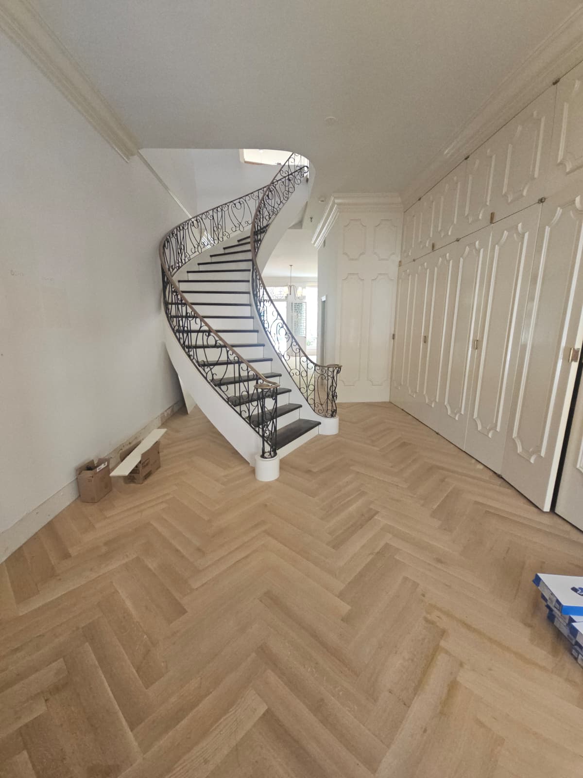 Finished white oak herringbone in the entry hall with the curved staircase