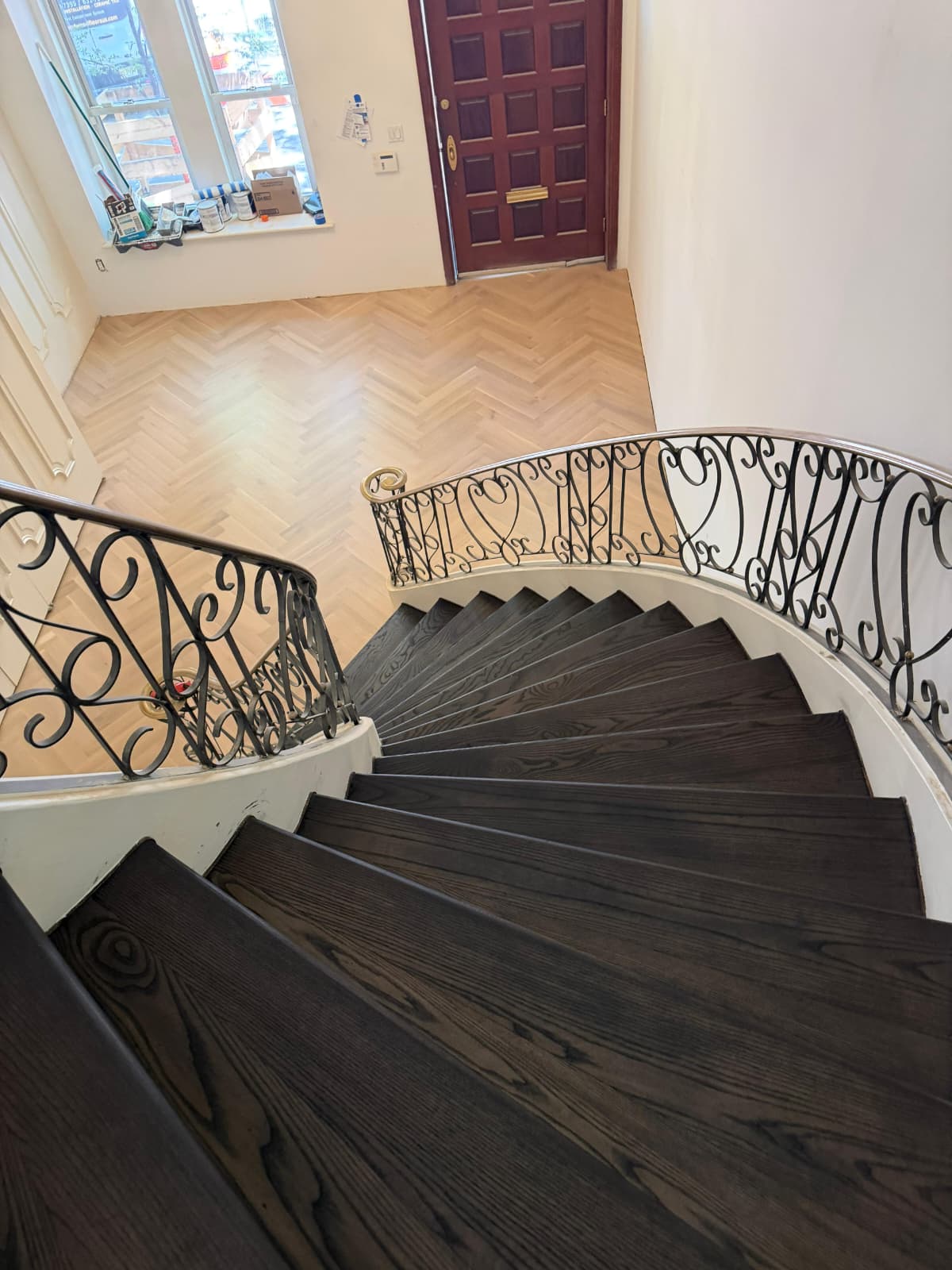 View down the curved staircase to the finished herringbone entry floor