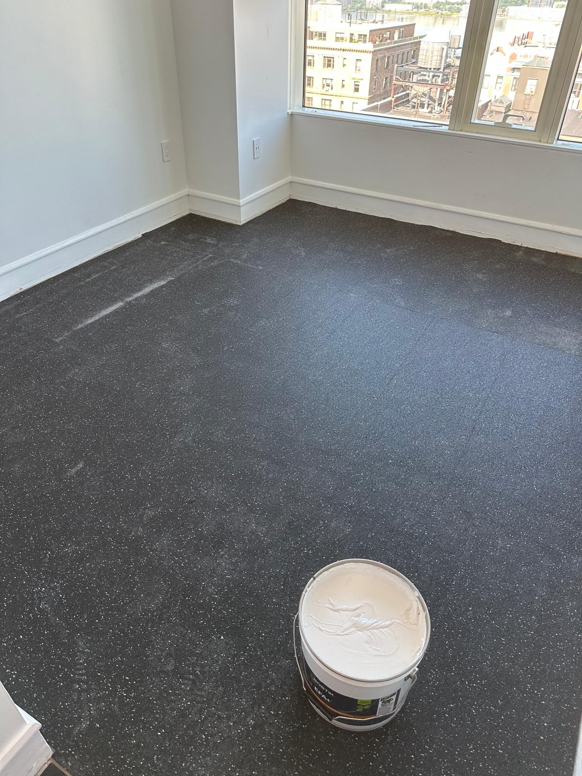 Soundproofing underlay glued down over the leveled slab, adhesive ready
