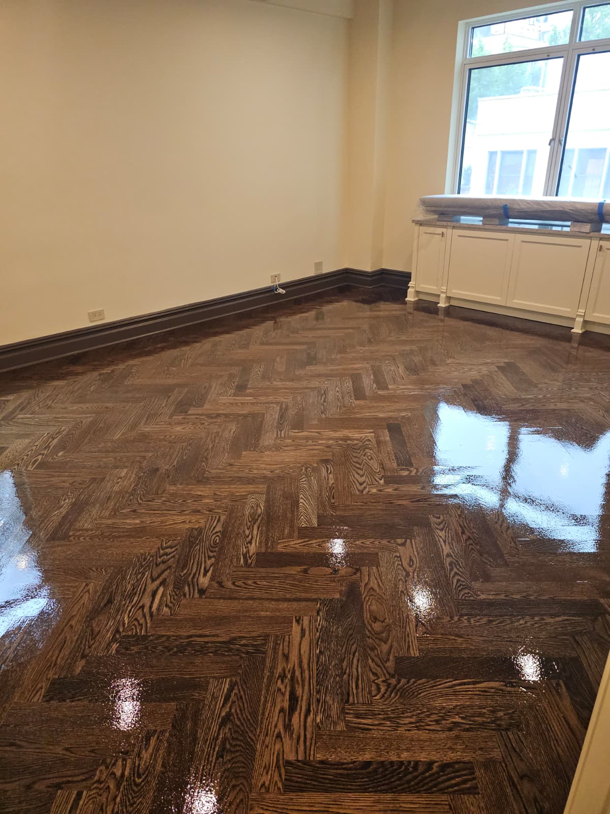 Fresh gloss coat over the dark walnut stained white oak herringbone in an Upper East Side pre-war co-op