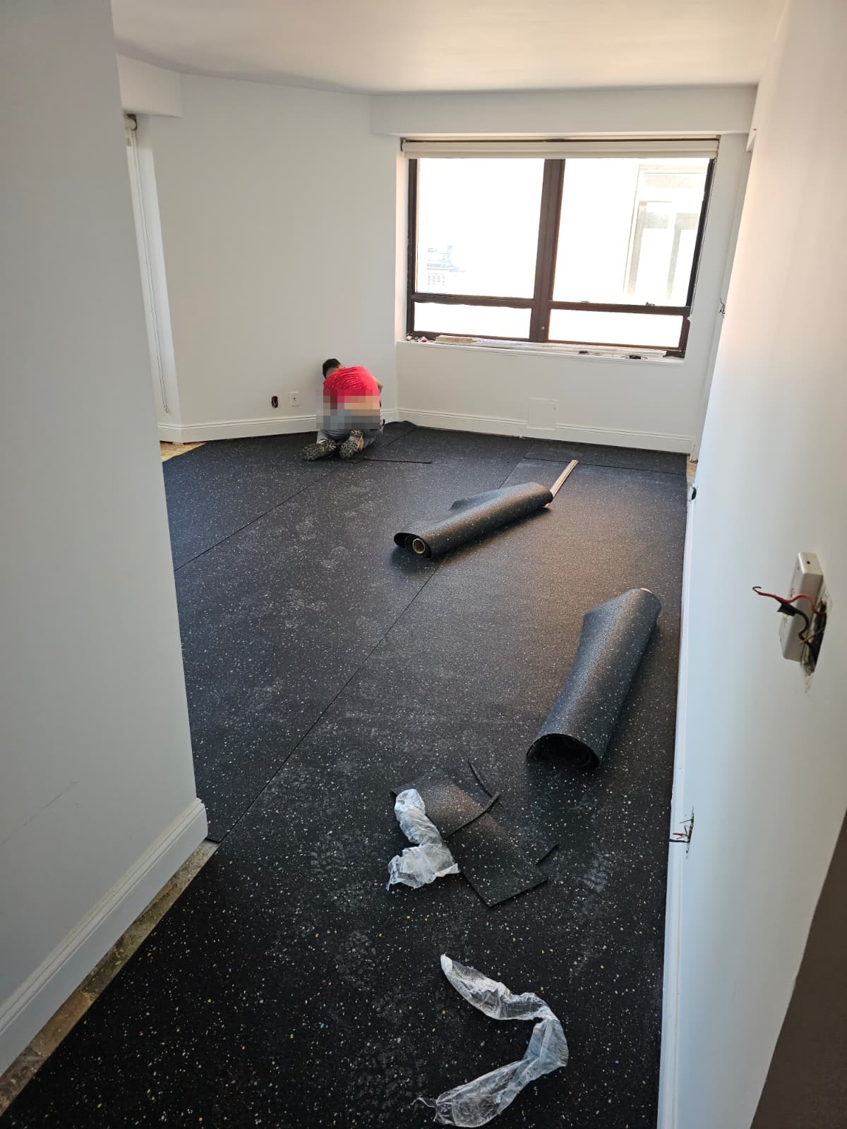 Soundproofing underlayment rolled out over the leveled concrete slab in a Midtown East apartment
