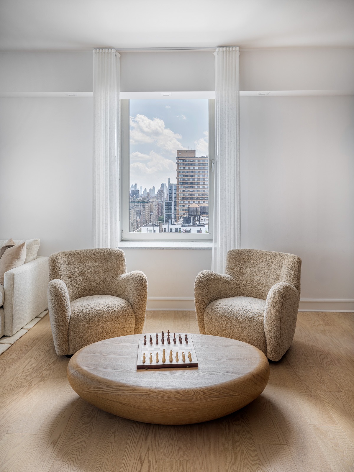 Completed living room with the new wide plank oak floor, boucle chairs and a chess table in a SoHo apartment