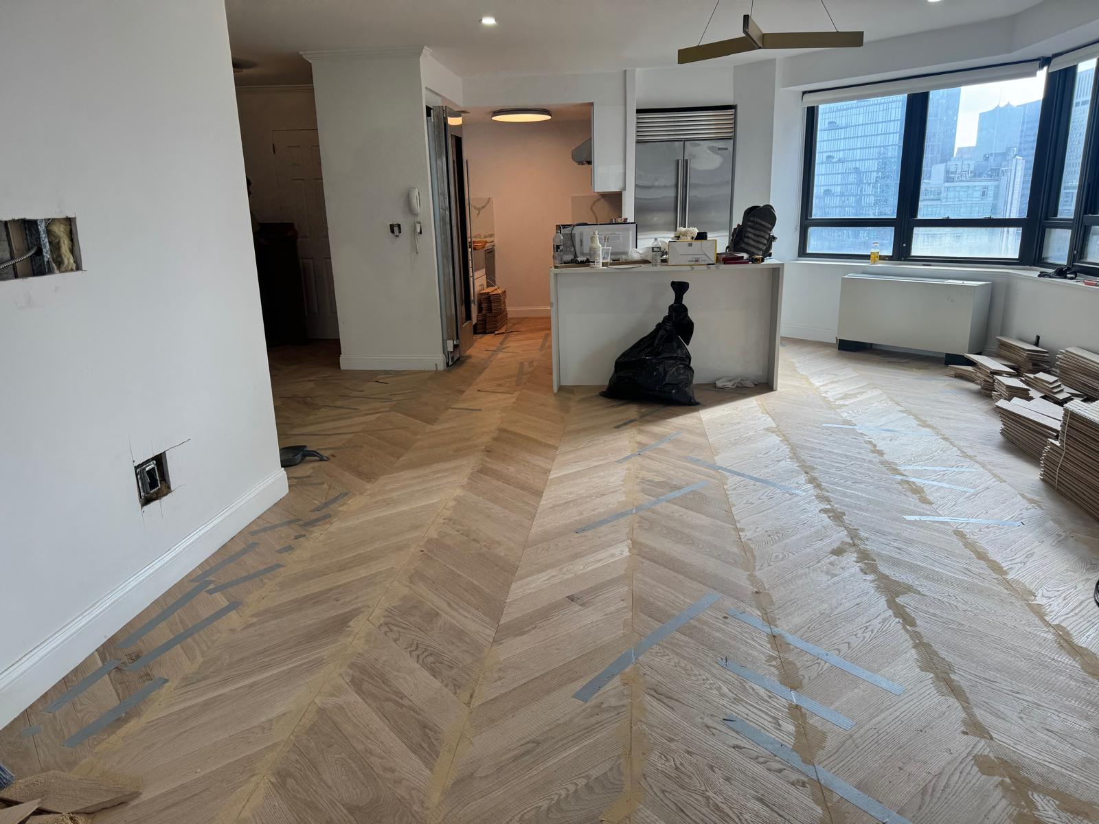 Newly installed unfinished white oak chevron across the living room and kitchen