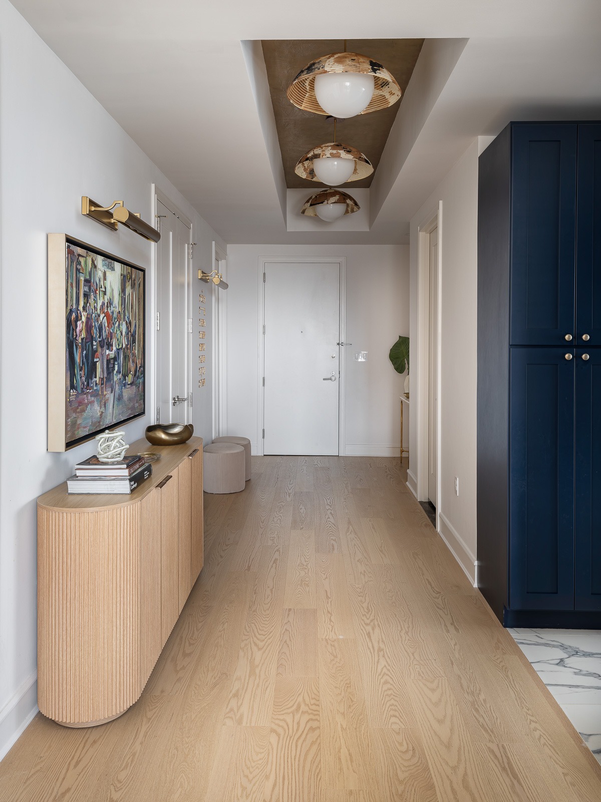 Completed entry hall with the new wide plank oak floor, console and navy cabinet in a SoHo apartment